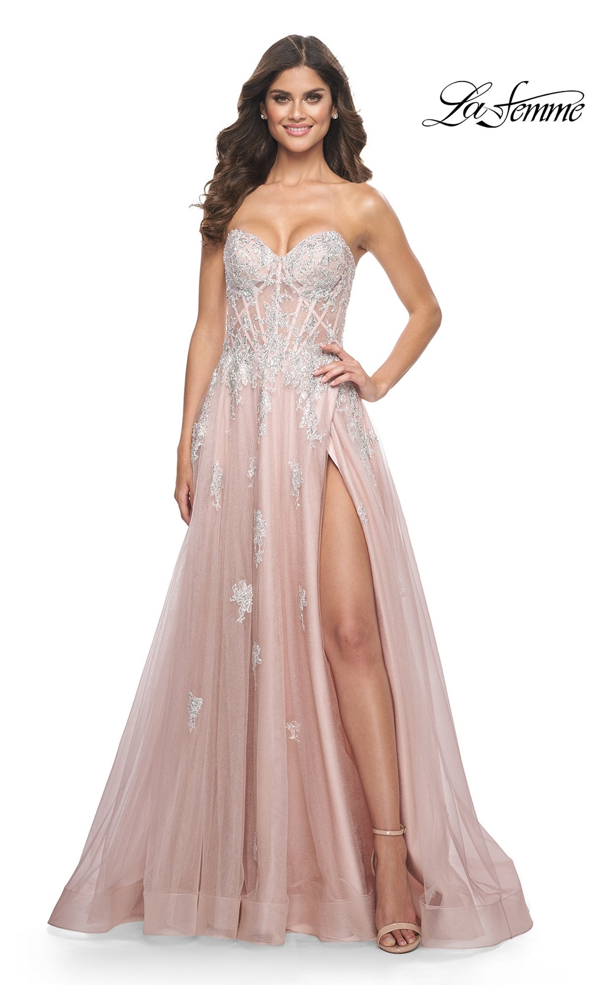 A woman stands smiling in the La Femme Strapless Long A-Line Prom Dress 32111, a light pink strapless gown with silver embroidered-lace appliques and a high thigh slit. The La Femme logo appears in the top right corner.